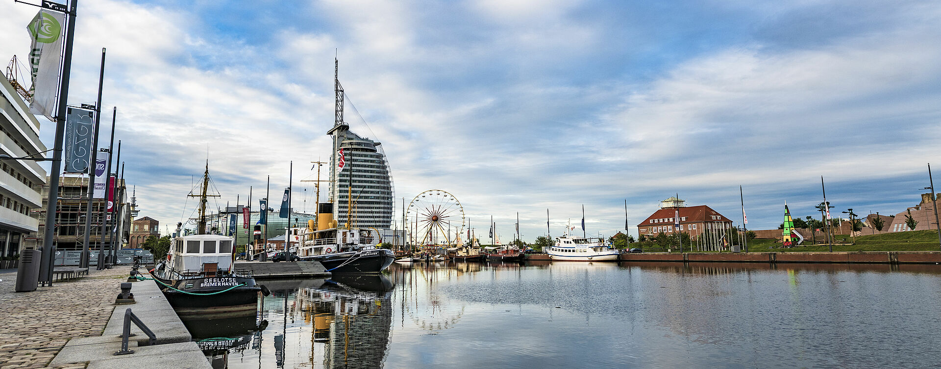 Blick über das Hafenbecken Neuer Hafen in Bremerhafen von Landseite aus. Im Hintergrund das Hotel Sailcity. Im Mittelgrund links liegt die Wal und ein Lotsenboot