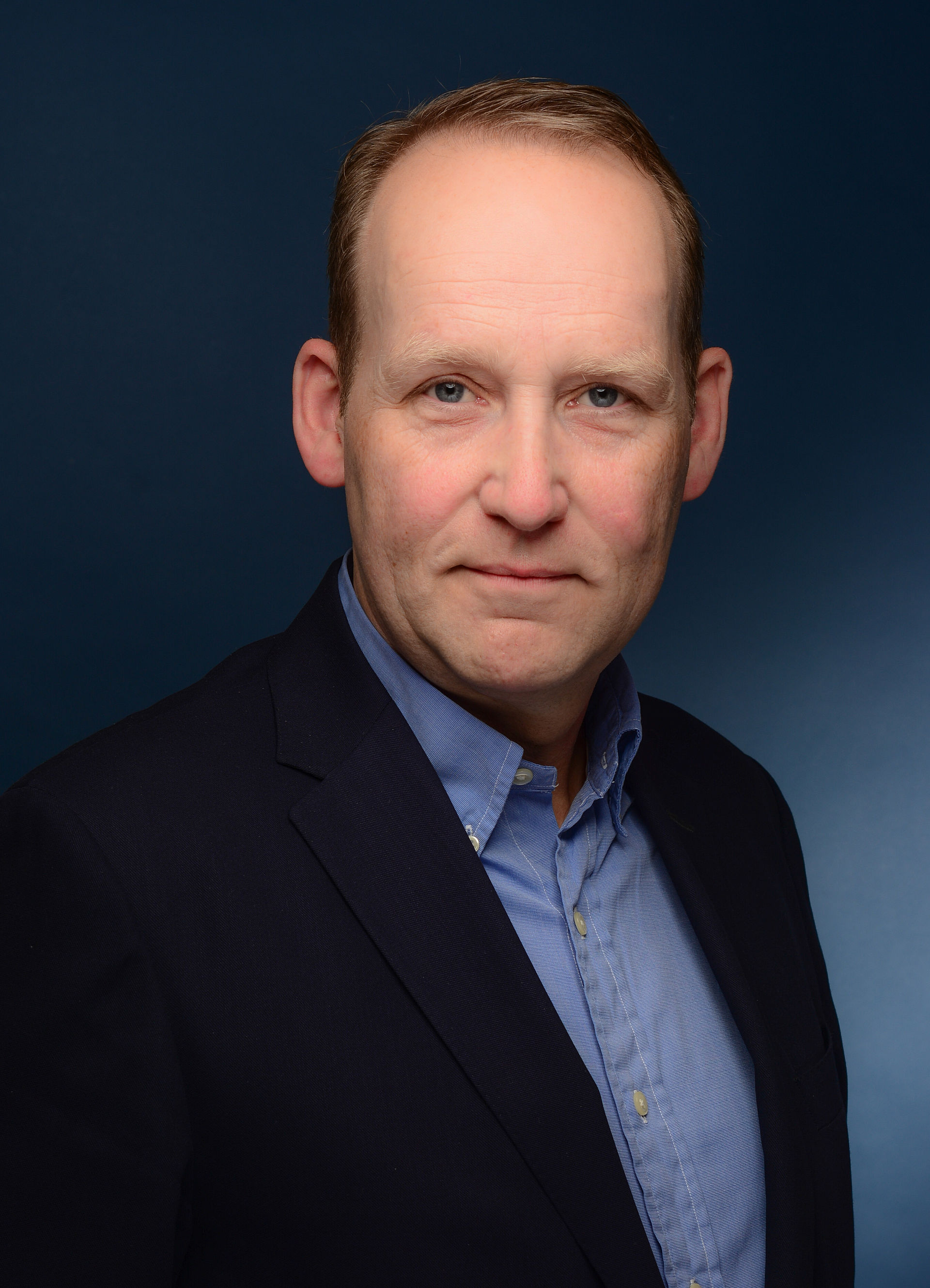 Portraitfoto von Ulrich Balke in einem schwarzen Sakko und blauen Hemd.